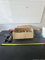 Three Bostitch pneumatic nail guns next to a cardboard box of coil nails.