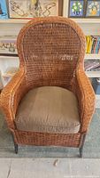 Front view of wicker armchair with cushion showing overall design and condition