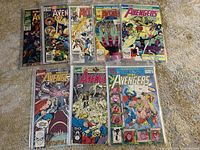 Front view of 9 Avengers comic books laid out on carpet in protective sleeves showing various annual and special issues.