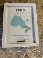 Photo of a framed printed map illustrating Toronto, Ontario as a zombie safe zone with marked safe locations and a legend.