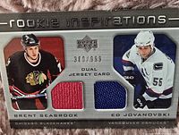 Front of the 2005-06 Upper Deck Rookie Update dual jersey card numbered 389/999 featuring Brent Seabrook and Ed Jovanovski with embedded red and blue jersey swatches.