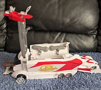 Side profile photo of the closed vehicle transporter with red and white color scheme on a carpeted surface