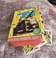 Sealed packs of Topps New Kids On The Block trading cards inside original colorful yellow display box with band images.