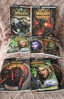 Eight World of Warcraft game boxes including expansions Mists of Pandaria, Cataclysm, and others in good condition.