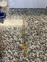 Full view of gold curb chain necklace with pendant laid flat on granite surface