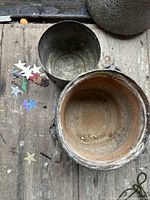 Top-down view of interiors showing aged patina and corrosion inside both containers, along with loose confetti stars on the wooden surface.