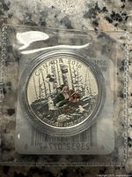 Front view of coin showing 2016 Woodland Elf design with colored accents, sealed in plastic pouch.