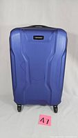 Front view of a blue Samsonite hard shell suitcase showing the textured design and brand logo plate.