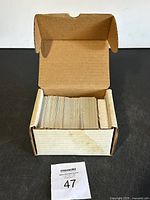 Opened cardboard box showing a large stack of basketball cards inside, arranged vertically.