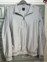 Front view of light grey Adidas windbreaker pullover with 1/4 zip and elastic cuffs.