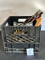 Plastic crate filled with various hand tools including saws, screwdrivers and pliers.