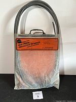 Front view of metal case with flexible coiled steel cable, orange label 'heavy duty drain clearer' visible