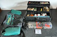 Overall view of the tackle box, Red Wolrd tackle kit and Stansport fanny pack placed on a surface