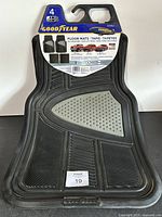 Front view showing a single black Goodyear floor mat with gray traction pad and packaging card.