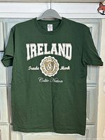 Green short-sleeve t-shirt on hanger showing Ireland Celtic Nation design.