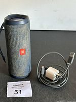 JBL portable speaker with charging cable and wall adapter, showing front with logo