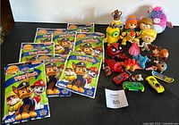 Overview of all items: eight Paw Patrol Play Pack activity packs, assorted small character toys including princesses, small toy cars