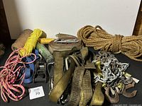 Photo showing all straps, ropes, chains, and hooks laid out with identification tag 70 visible