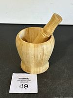 Front view of the wooden mortar with pestle inside, showing the smooth wood grain and rounded shape.