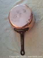 Bottom view of the copper pot showing the round hammered surface and attached black handle with loop for hanging.