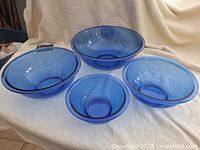 Set of 4 blue Pyrex glass mixing bowls displayed on a white towel background