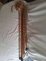 Photo showing all five wooden walking canes laid side by side to display variety in lengths and hooked handles.