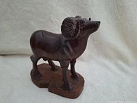Side angled view of big horn sheep wooden carving showing detailed horns and posture.
