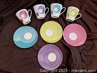Top view of set showing 4 espresso cups each with a different colored circle and 4 matching saucers in pastel pink, purple, blue, and yellow.