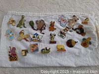 Collection of assorted enamel and metal pins laid out on white cloth