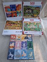 Photo showing 5 puzzle boxes stacked and arranged, each labeled with 500 pieces and displaying different images.