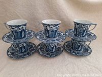Set of 6 Japanese style blue tea cups with matching saucers arranged in two rows of three, showing detailed traditional blue pattern designs on white porcelain.