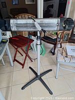 Front view of Veito carbon infrared heater on adjustable stand showing heating element, grill, power cord, and base.