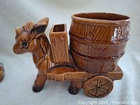 Close-up photo of brown ceramic donkey planter with barrel and cart, showing side and front details.