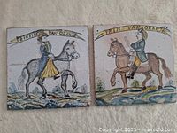 Front view of two ceramic tiles featuring Prince and Princess van Oranje on horseback, with inscriptions above each figure.