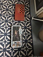 Photo of a closed Star Wars tin box game and closed vintage board game box on floor patterned carpet