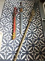 Photo showing full view of the three LARP weapons on patterned floor: bronze spear, grey sword, red scabbard.