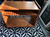 Front and side view of the teak TV table showing the open shelving and rectangular shape.