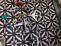 Overall assortment of toy airplanes, cars, and a pop can for scale on patterned rug