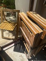 Five stacked teak chairs secured in metal rolling rack