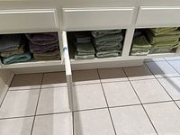 Shelves with stacks of assorted folded towels in various colors including green, purple, and grey.