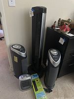 Photo showing two GermGuardian HEPA air purifiers, Seville rotating fan, and two Mini Brightown heaters together on carpeted floor.