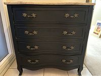 Front view of French Provincial wood bureau with cream marble top, highlighting four drawers with decorative metal handles and cabriole legs.