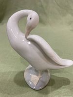 Front view of Lladro swan figurine in preening pose, white porcelain with delicate sculpting