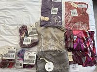 View of multiple scarves laid out on white surface, showing tags and packaging, featuring Coldwater Creek branded scarves and Demdaco painted silk scarf.