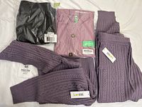 Lot of new women's clothes including purple knit cardigan and pants, black faux leather leggings in package, and DKNY sport set.