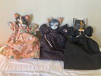 Three hand-painted reversible cat dolls arranged side-by-side, showing the awake faces on one side.