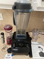 Vitamix 5200 blender base with large clear container, Ninja red personal blender and milk frother on countertop.