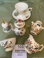 Full lot overview showing creamer, sugar bowl, teapot, cup and saucer, small vase, and Christmas bell.