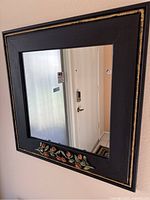 Front view of square wall mirror hanging on a wall.