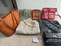 View of all seven bags in the lot together on a carpeted floor showing variety in size and style